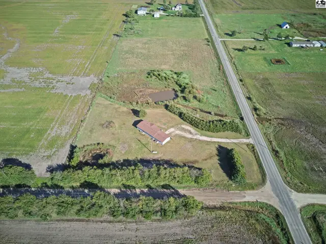 This property features a house, a gravel driveway, and surrounding fields.
