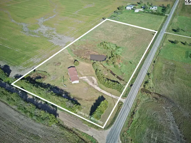Spacious lot with a single-story house and a small pond.