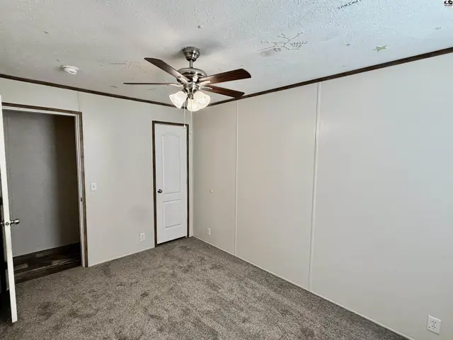 Carpeted room with a ceiling fan, closet, and interior door.