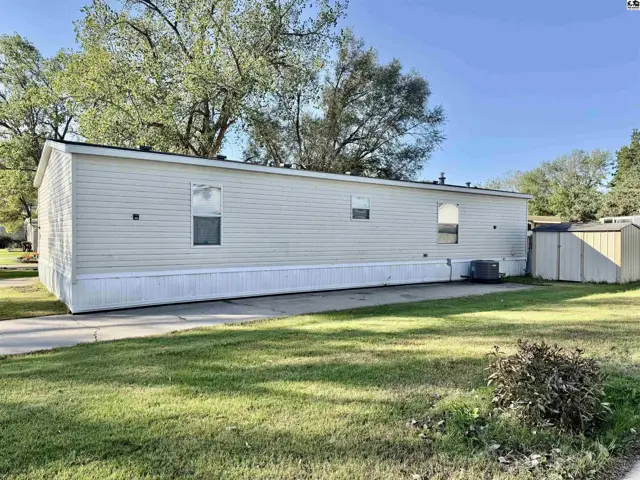 Manufactured home with vinyl siding and a detached storage shed on a concrete pad.