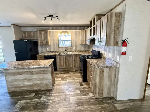Spacious kitchen features wood-grain cabinetry, granite countertops, and a central island.