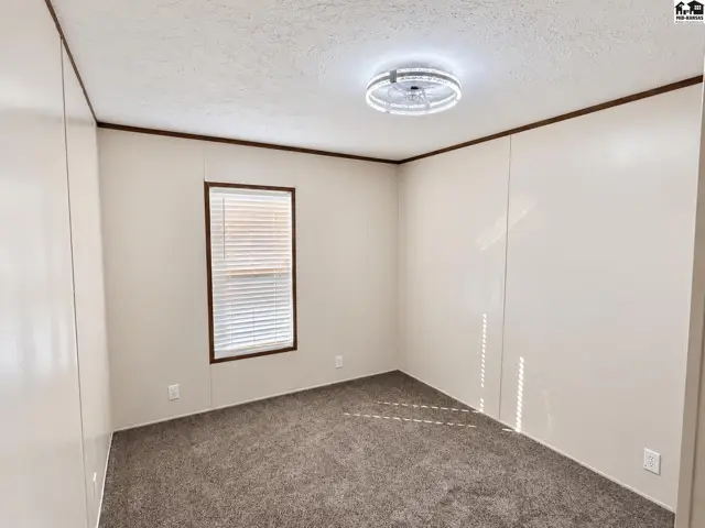 Carpeted room with a ceiling fan and a window with blinds.