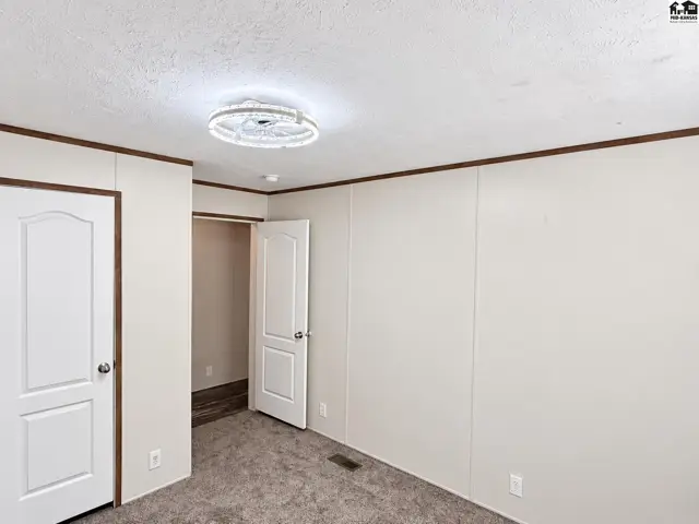 This room features carpeted floors, white paneled walls, and a ceiling fan.