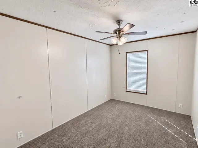 Carpeted room with a ceiling fan and a window with blinds.
