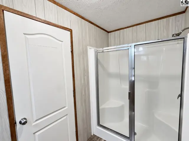 White paneled walls and a sliding glass shower enclosure accent this bathroom.