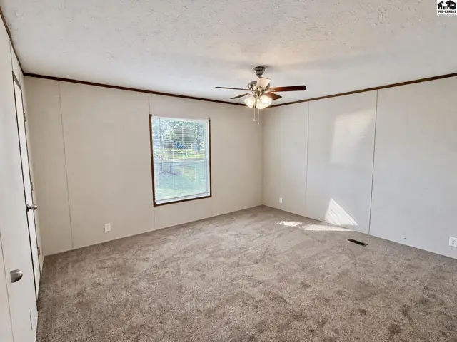 Spacious room with carpet, a ceiling fan, and a large window.