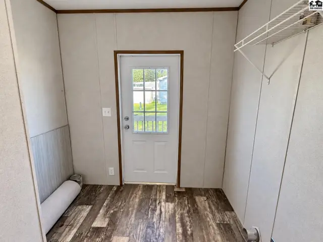 This room features wood-look flooring, paneled walls, and a white door with a glass insert.