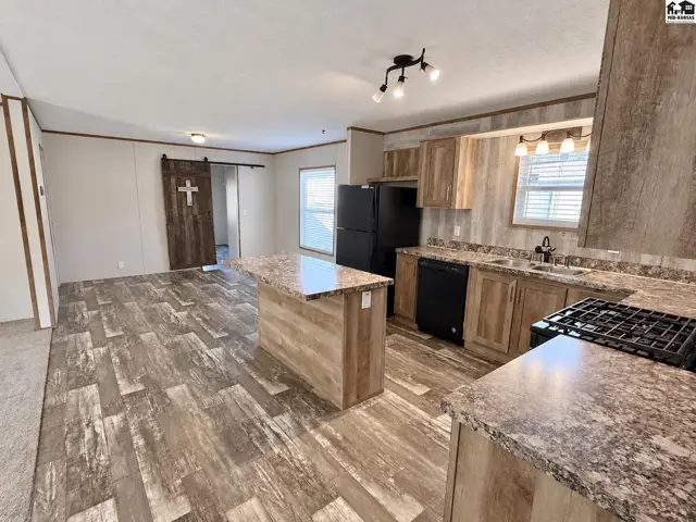 This kitchen features wood-look flooring, granite countertops, and a large island.
