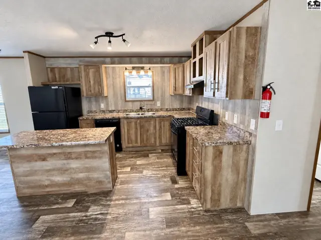 This kitchen features wood-grain cabinetry, granite countertops, and a central island.