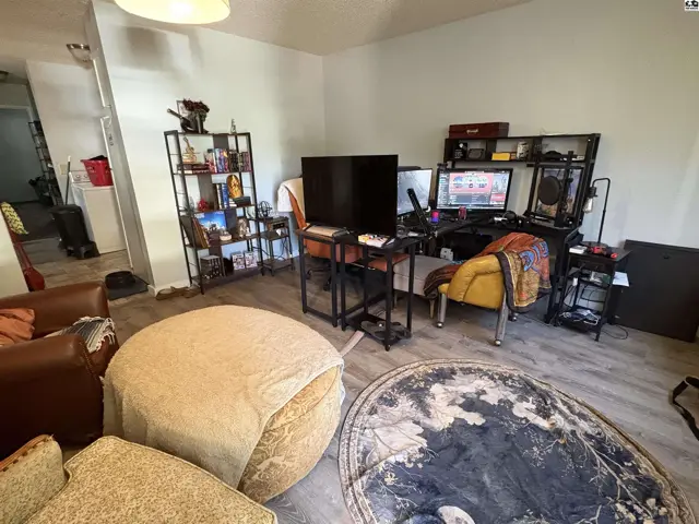 This living area features wood-look flooring, a large ottoman, and a media console.