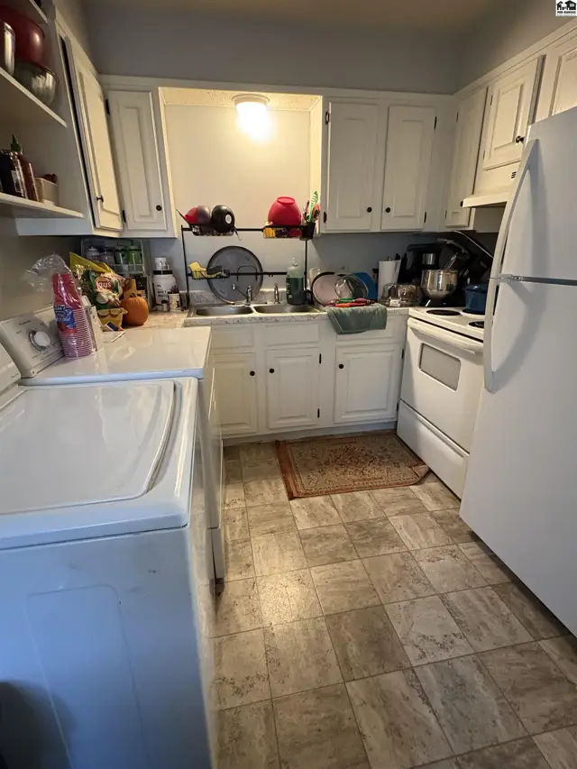 White cabinets, countertops, and appliances fill this compact kitchen with a tiled floor.