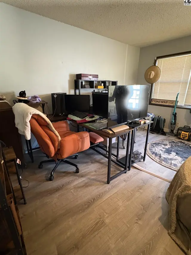 This room features light grey walls, wood-look flooring, and a large window with blinds.