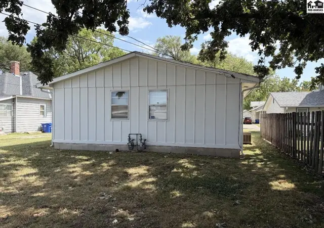 White vinyl siding exterior with two windows and a gas meter on a grassy lot.