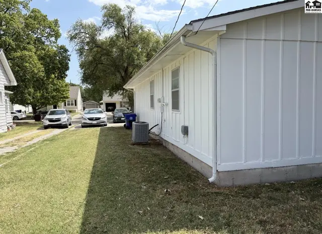 White vinyl siding covers this home with a green lawn and driveway.