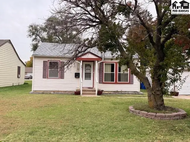 This white vinyl-sided house features a red-trimmed front door and windows.