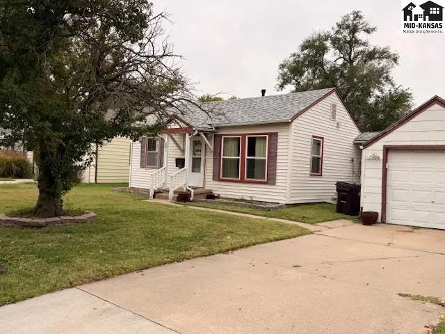 White siding home with a detached garage and mature tree in the front yard.