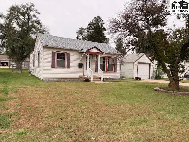 This white vinyl-sided house features a covered front porch and a detached garage.