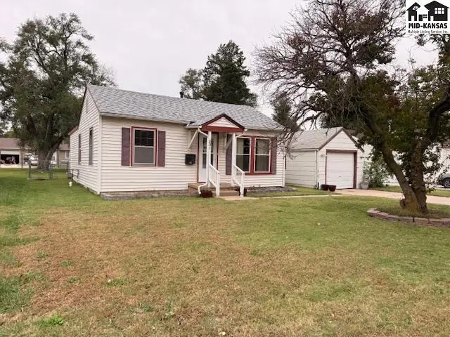 This single-story home features white siding, a detached garage, and a grassy yard.