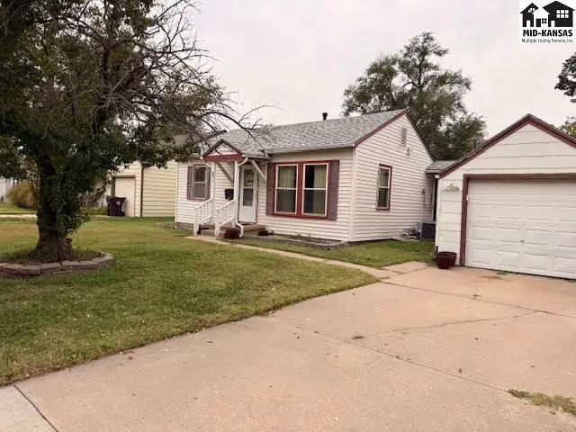 White siding house with a detached garage and a mature tree in the front yard.