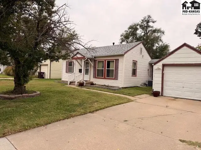 This white vinyl-sided house features a detached garage and a concrete driveway.
