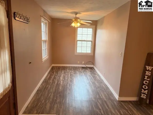 This room features wood-look flooring, two windows, and a ceiling fan.