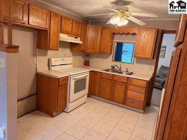 This kitchen features oak cabinetry, a white stove, and tile flooring.