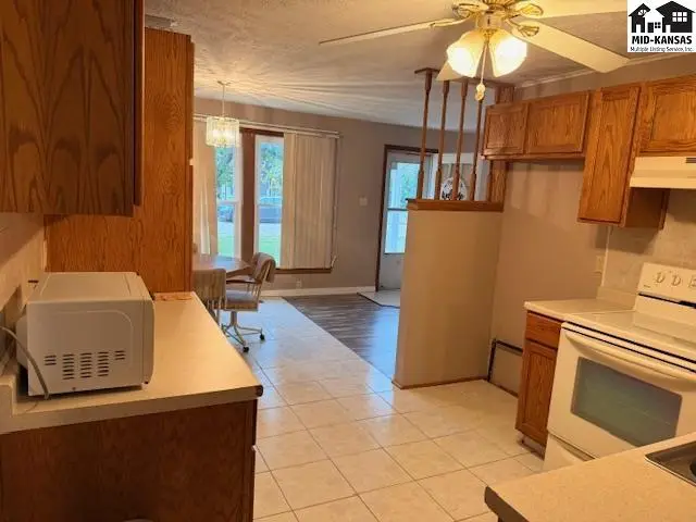 Kitchen features white tile floors, wood cabinetry, and a white range.