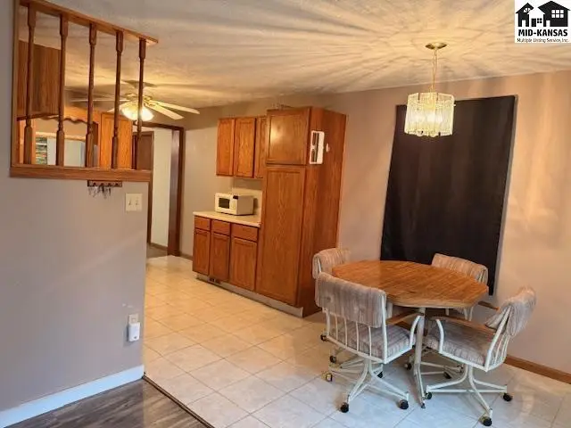 This dining area features a round table with four chairs and a view of the kitchen's wood cabinets.