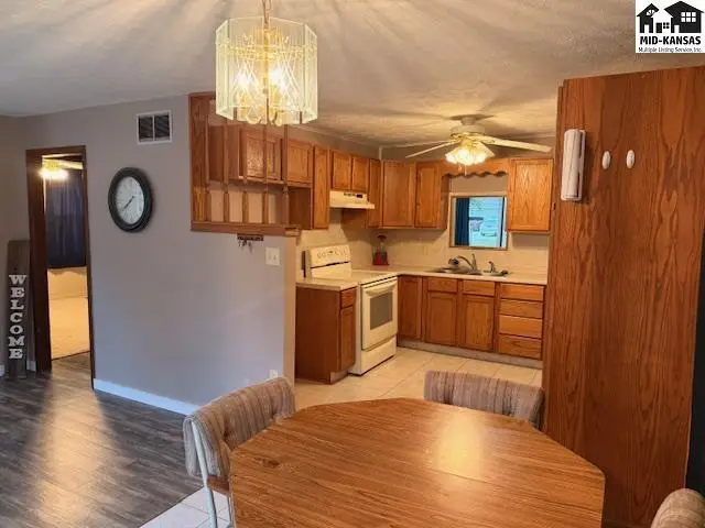 This kitchen features wood cabinetry, a white stove, and a dining area with a round table.