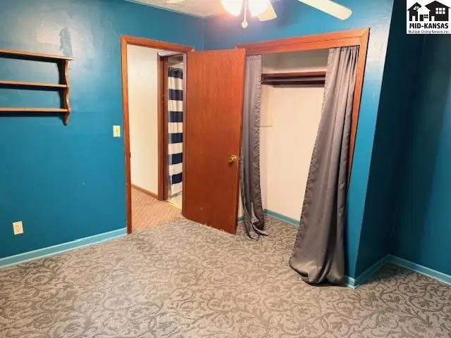 Carpeted room with blue walls, a closet with grey curtains, and a doorway to another room.